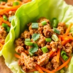 Close-up of a low carb chicken lettuce wrap filled with spiced chicken and vegetables.